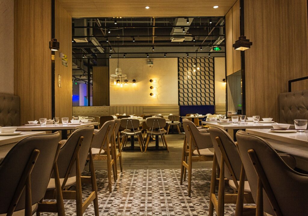 Interior de un restaurante con mesas, sillas y platos encima